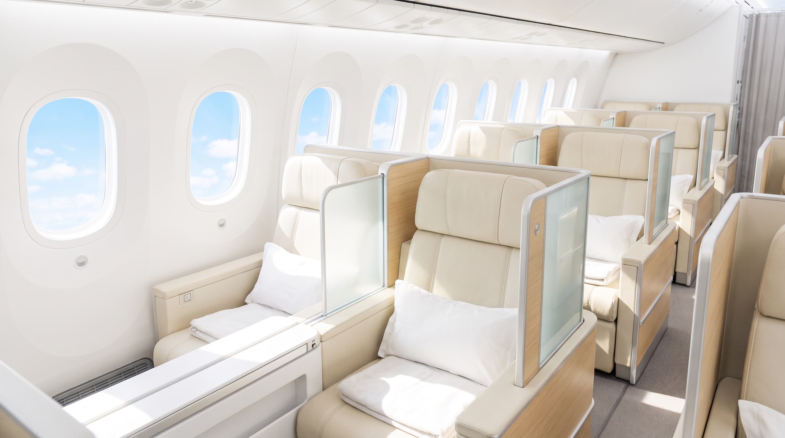 Empty business class cabin in bright daylight with blue sky through the windows